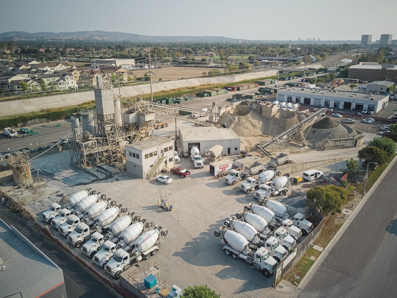 Aerial shot of a bustling cement manufacturing plant with mixer trucks and industrial equipment.